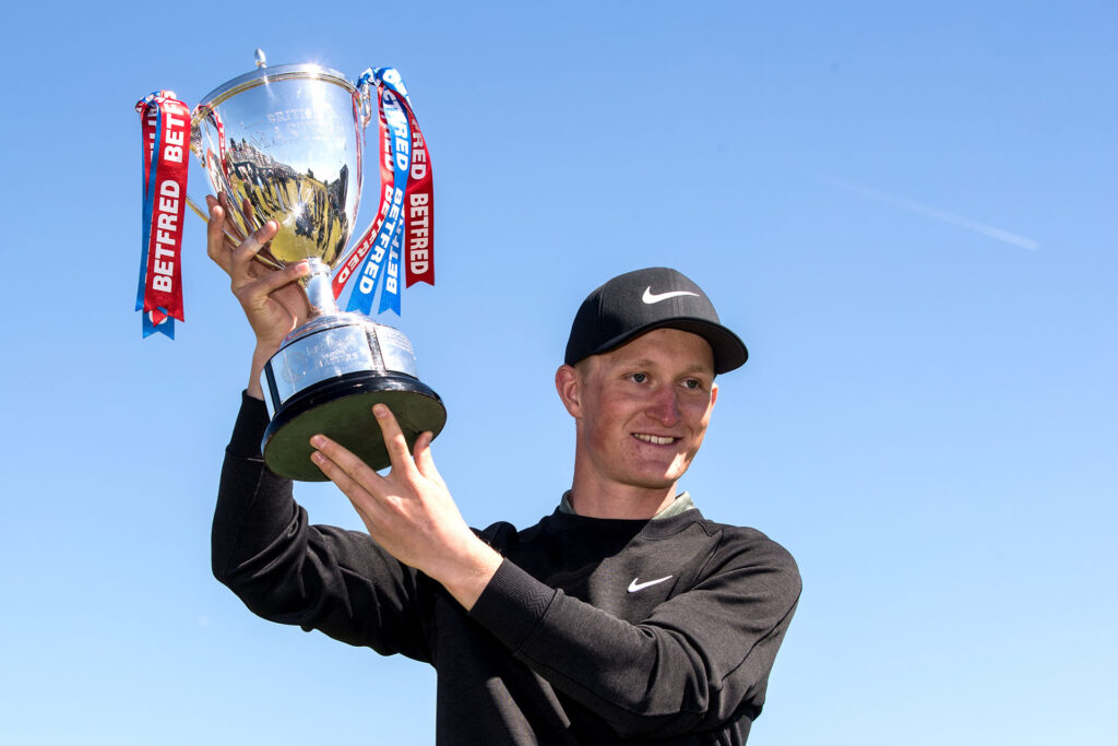Marcus Kinhult of Sweden lifts the trophy after winning the Betfred British Masters at Hillside Golf Club